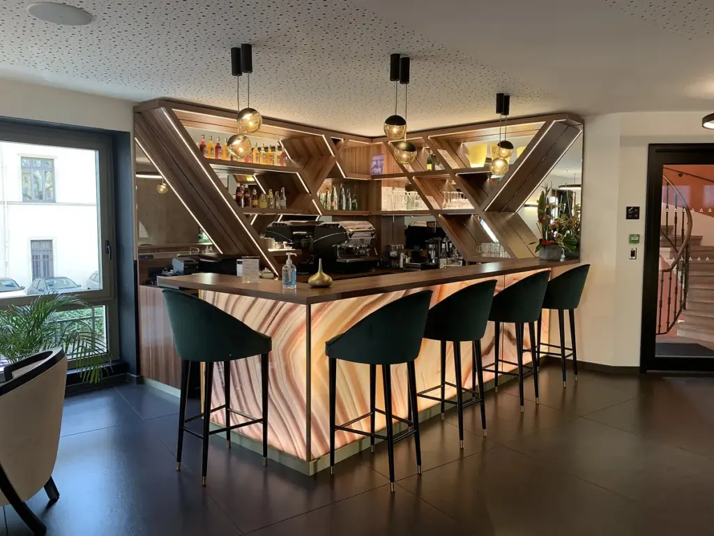 Bar com balcão de madeira, banquetas altas e prateleiras iluminadas