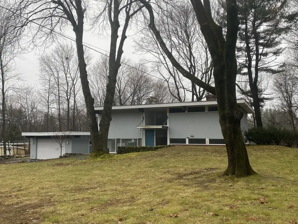 Casa moderna térrea de telhado plano em um terreno gramado com árvores