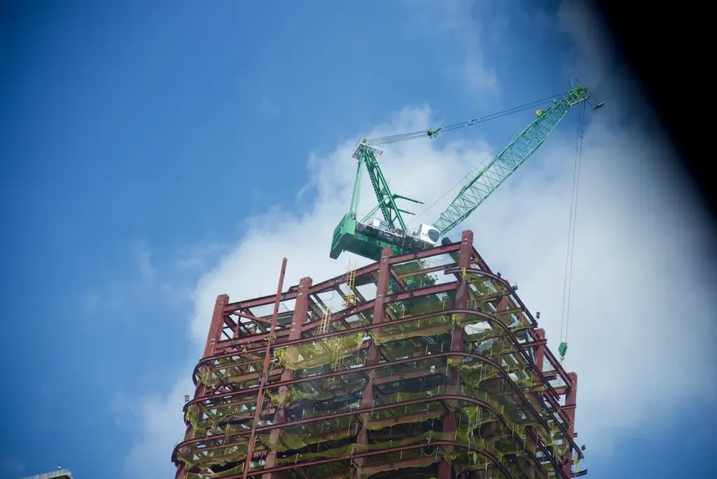 Prédio de estrutura metálica em construção com uma grua verde no alto