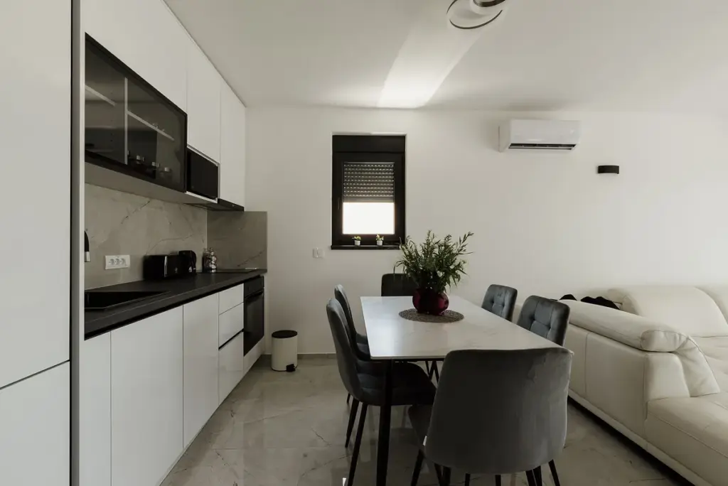 Cozinha branca integrada à sala de jantar, com armários planejados e mesa para seis