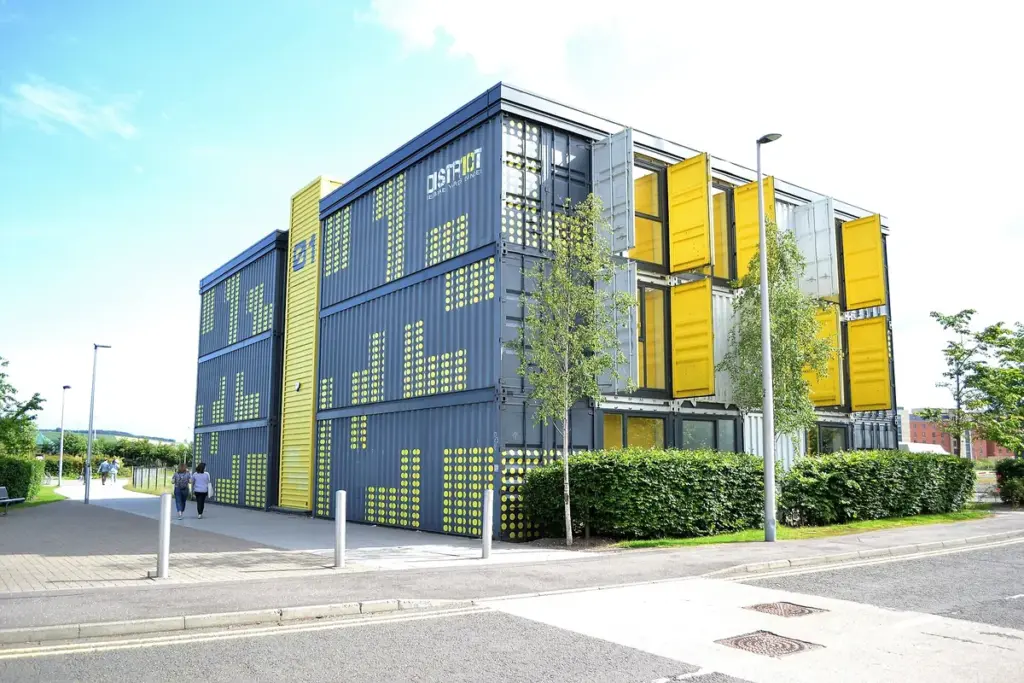 Prédio de três andares construído com contêineres pintados de azul e amarelo